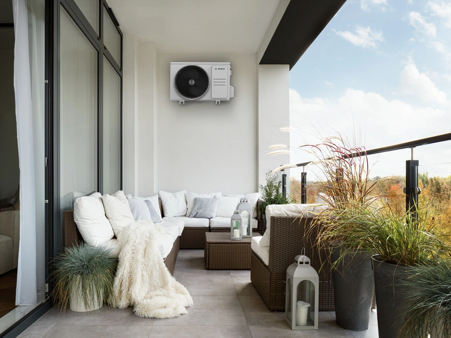 Modernes Außengerät einer Klimaanlage von Bosch auf einem stilvoll eingerichteten Balkon an der Wand montiert