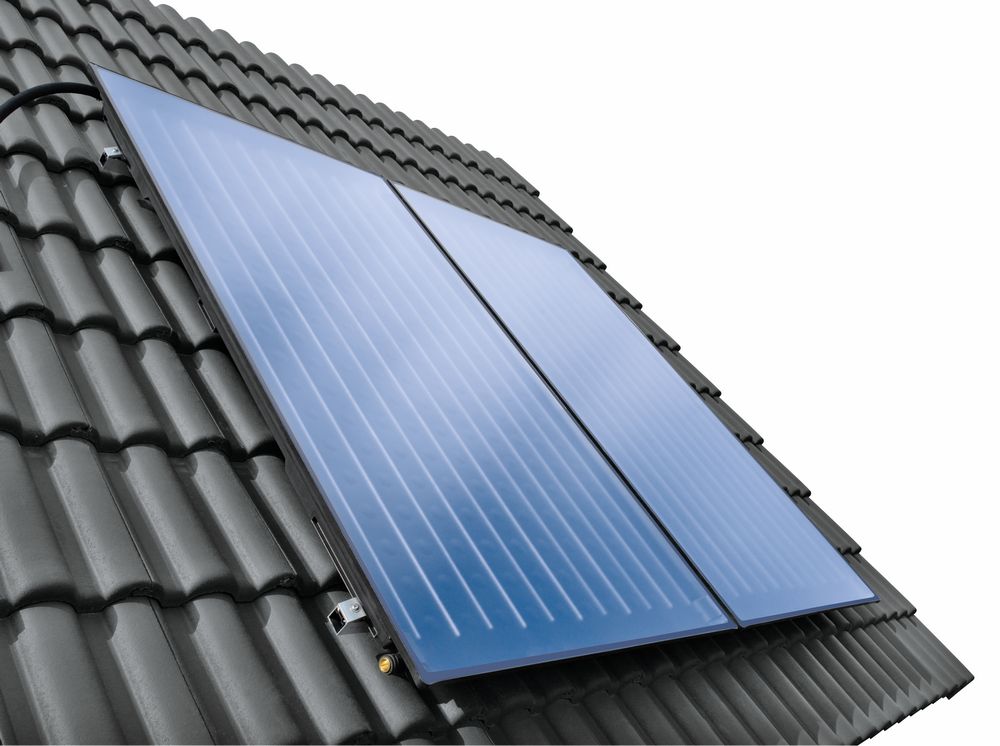 Zwei blaue Flachkollektoren auf einem schwarzen Ziegeldach montiert, zur Nutzung von Solarthermie. Die Oberfläche ist glatt mit sichtbaren Linien.