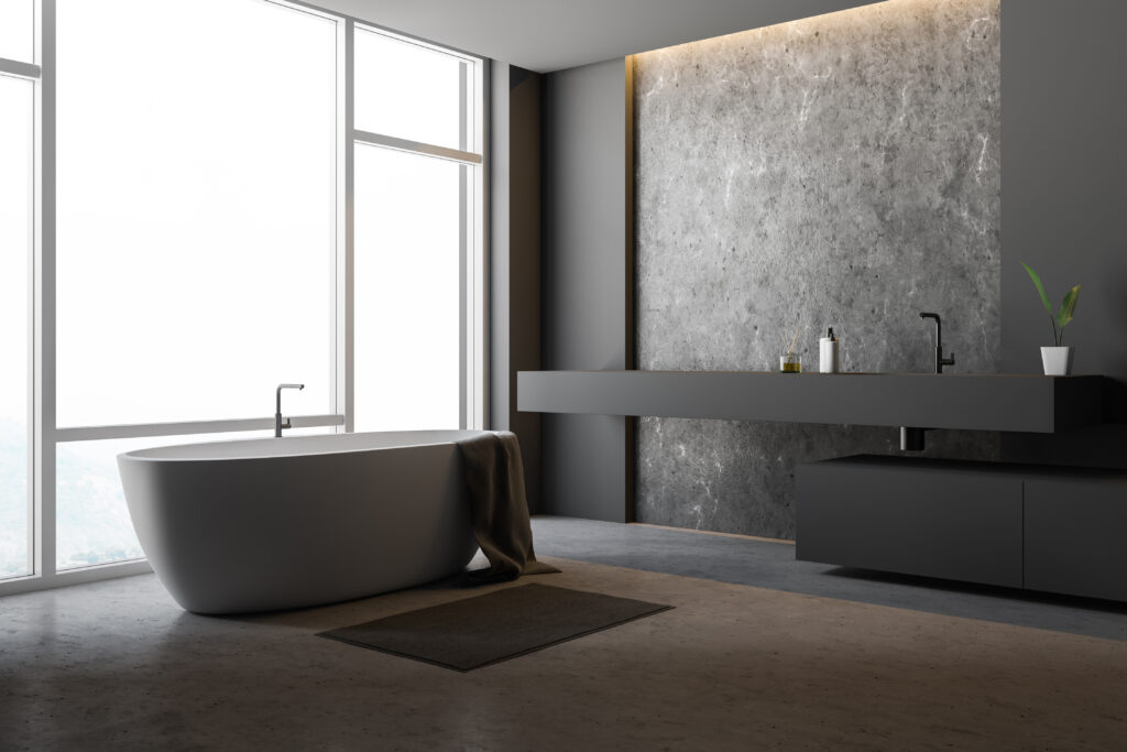 Modernes, minimalistisches Badezimmer mit freistehender Badewanne und dunkler Waschtischwand aus Betonoptik